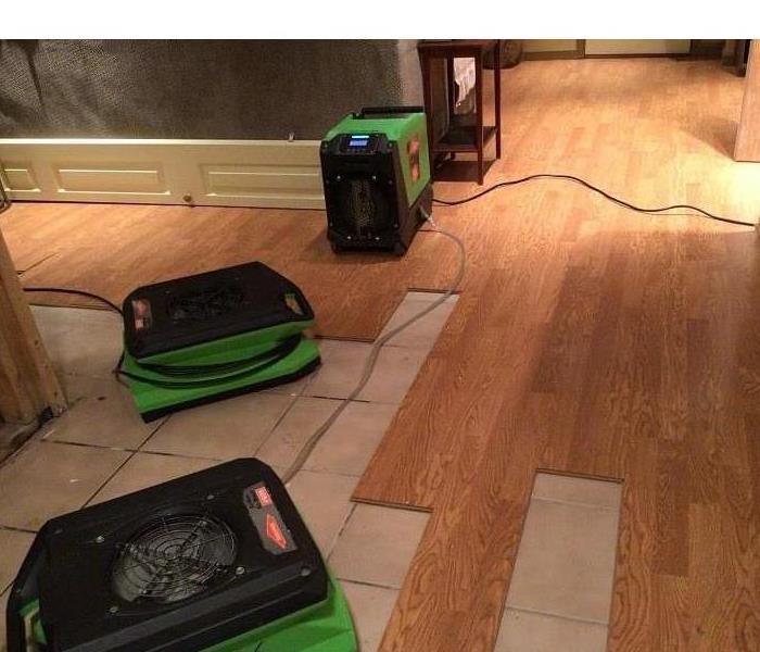 SERVPRO green drying equipment set up in front of leaked water softeners