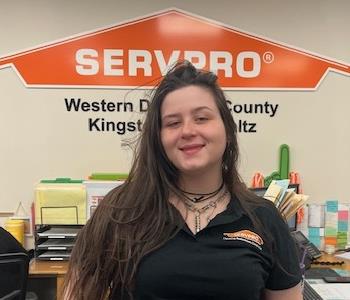 A photo of a smiling female SERVPRO employee with long brown hair in a black SERVPRO sweater