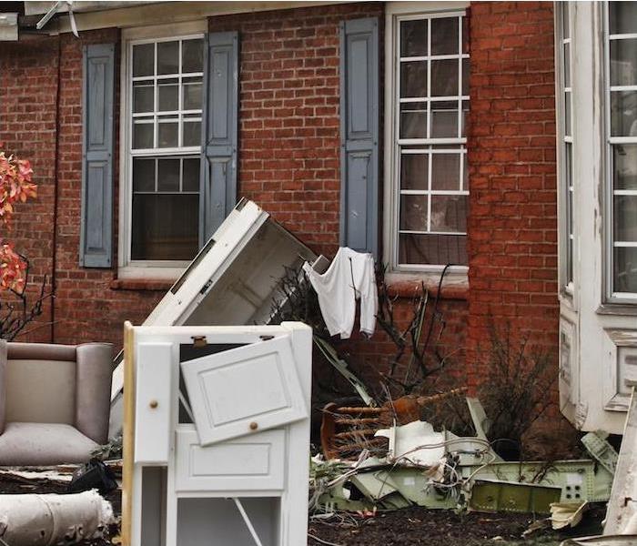 Damaged furniture and appliances sitting outside on the lawn of a home