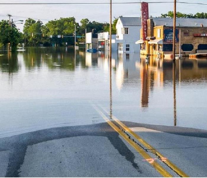 A street lined with businesses and flood waters up to their doors.