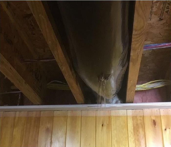 Water pouring through a hole in the ceiling out of sheet rock and insulation