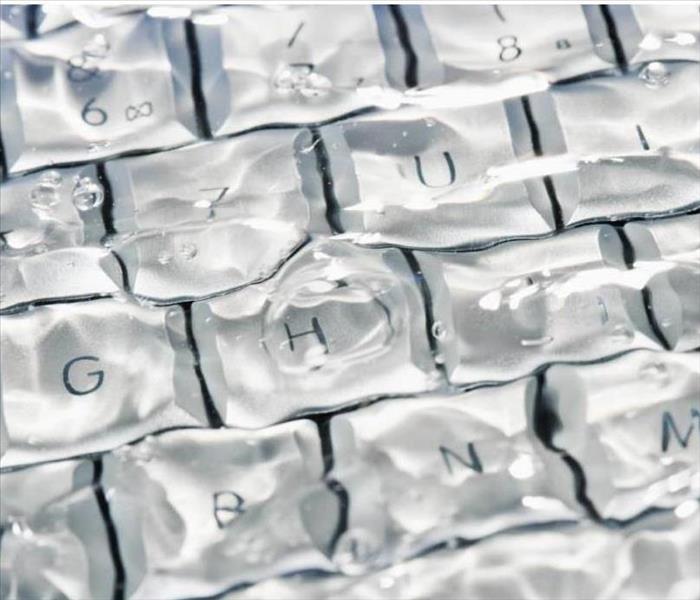A photo of a white computer keyboard submerged in water.