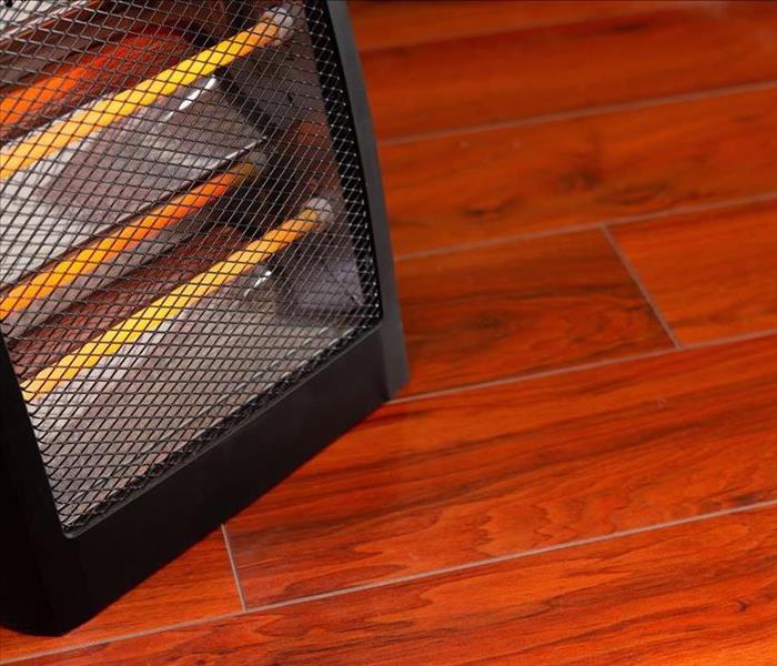 An image of a space heater running on a hardwood floor.