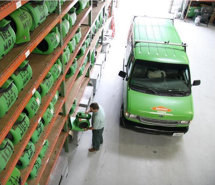 A green SERVPRO van parked in a warehouse full of green SERVPRO equipment