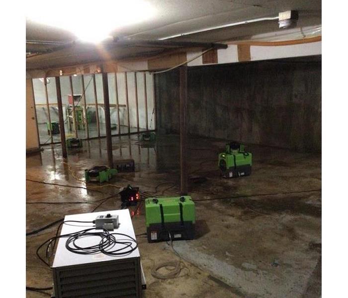 Am empty commercial size laundry room being dried out with SERVPRO green equipment placed in different areas.
