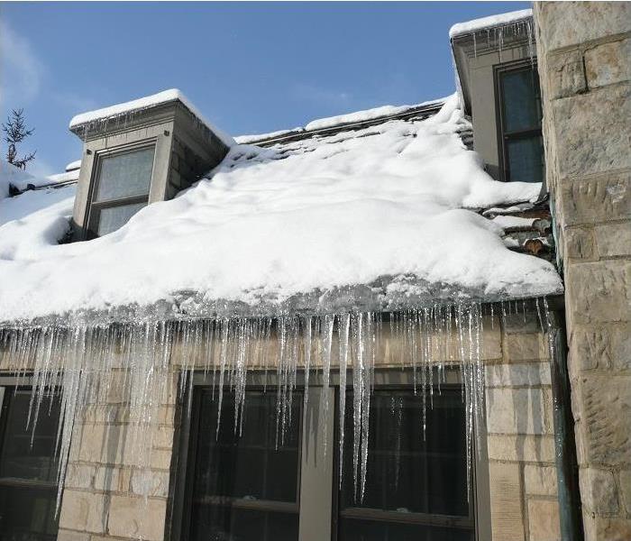Snow, ice and icicles hanging off of the gutters on a house