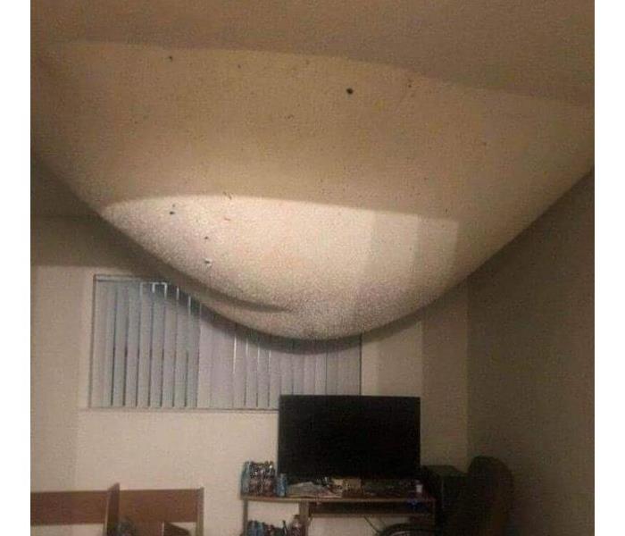 An enormous pain bubble in the ceiling filled with water from a pipe break above this bedroom