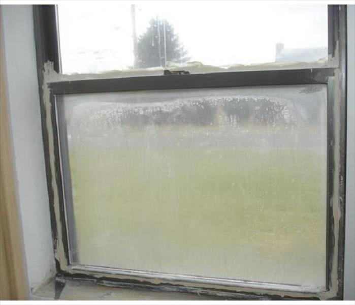 A double-pane window with condensation inside and insufficient caulking around it