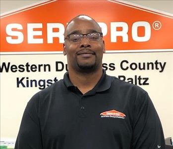 A photo of a smiling male SERVPRO employee wearing a black polo shirt