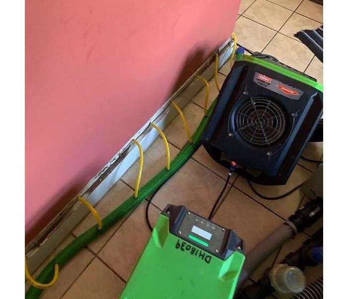 A photo of SERVPRO drying equipment placed next to a red wall
